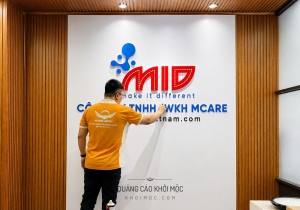 Backdrop logo mica nổi MCARE: nền vân đá, lam gỗ ấm