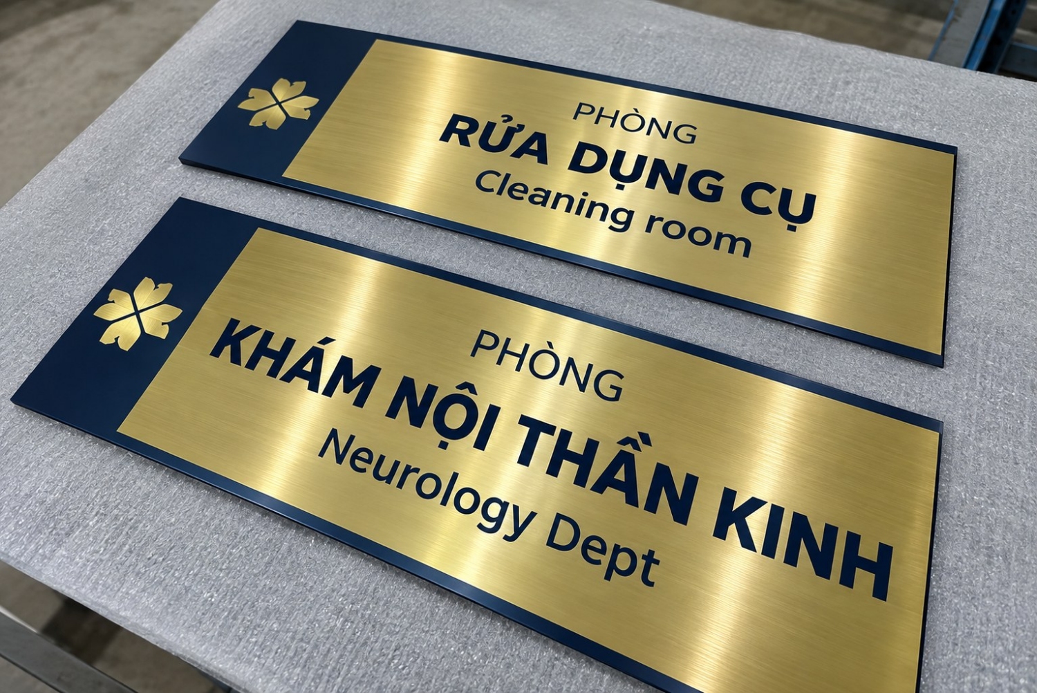 Bảng tên phòng bệnh viện inox mạ vàng nền xanh navy, song ngữ Việt - Anh, khắc Phòng rửa dụng cụ và Phòng khám nội thần kinh