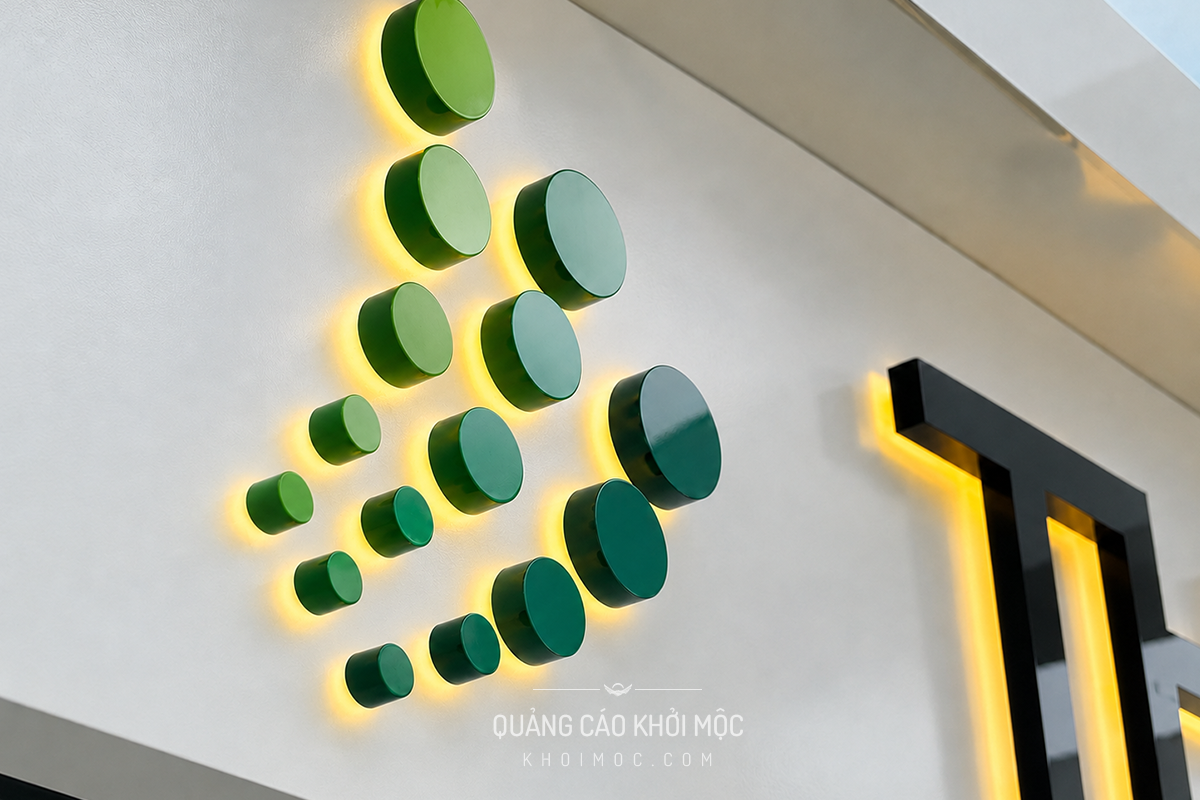 Logo dấu chấm xanh lá Thăng Long Instruments — mica đen in UV, uốn chân Fomex, hắt LED vàng nhạt dưới chân