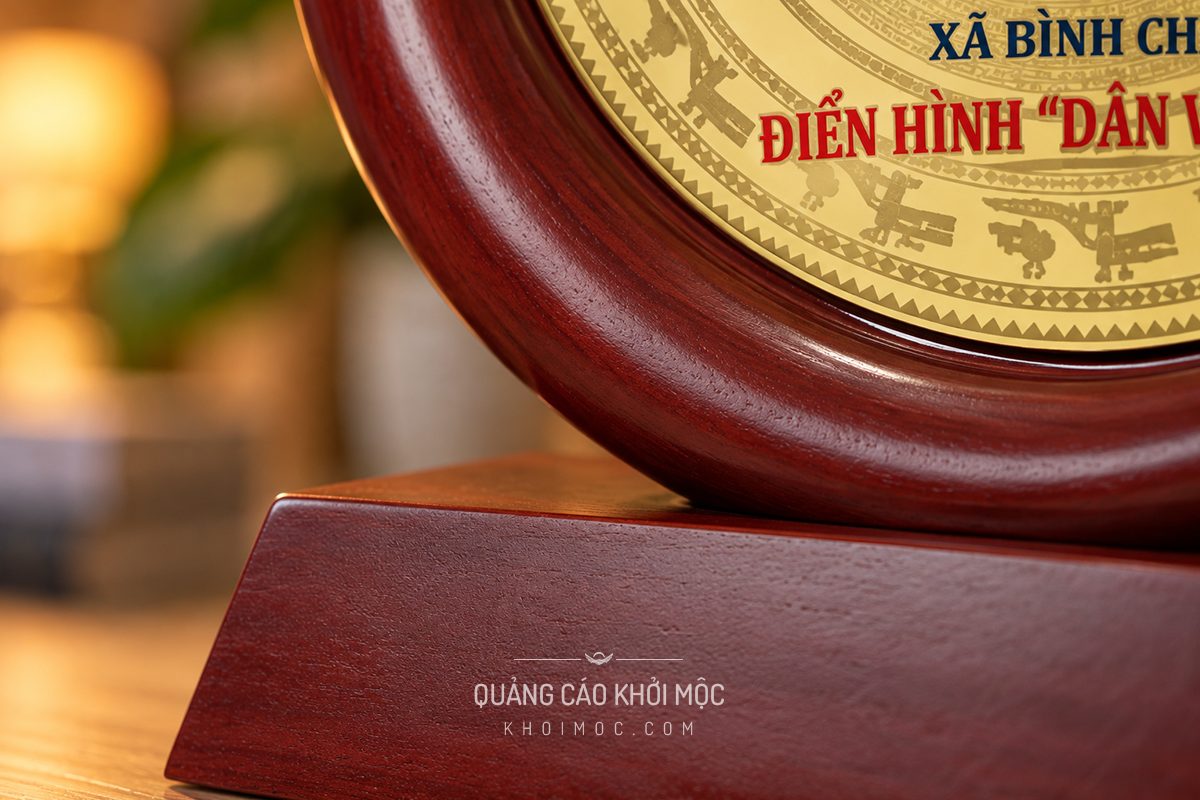Mẫu kỷ niệm chương gỗ tròn viền đỏ, huy hiệu tròn mạ vàng khắc chữ kỷ niệm, cận cảnh đế