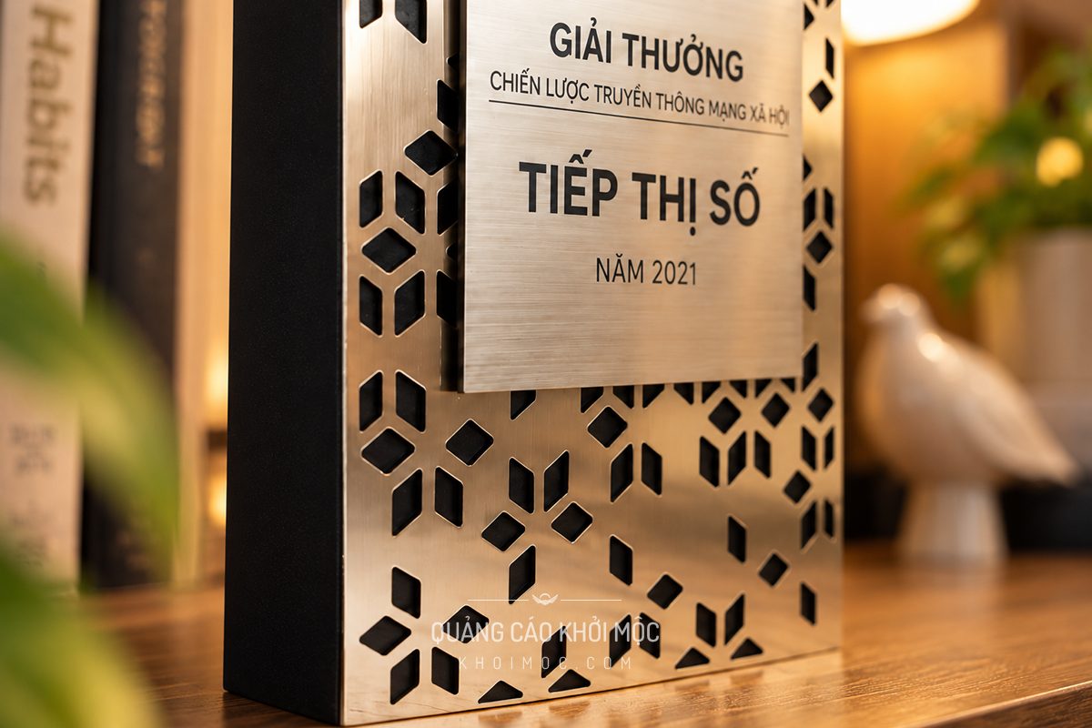 Mẫu kỷ niệm chương màu vàng hoa văn hình học, đế đen khắc tên giải thưởng, cận cảnh mặt khắc