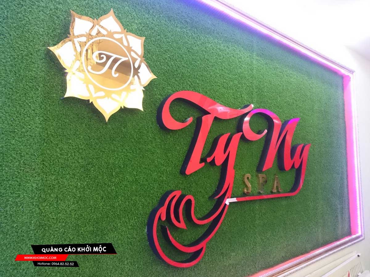 backdrop tiệm spa được làm từ cỏ nhân tạo kết hợp logo chữ nổi mica và inox